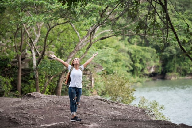 Young happy woman with backpack raising hand enjoy with nature. 