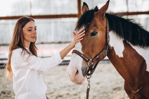 Young happy woman with horse at ranch