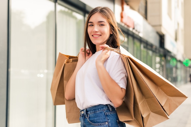 Young happy woman with shopping bags walking on street.