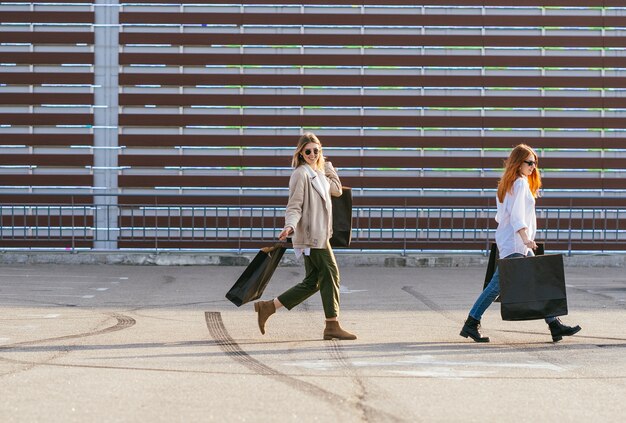 Free Photo young happy women with shopping bags walking on street.