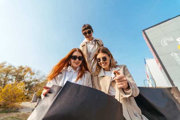 Free photo young happy women with shopping bags walking on street.