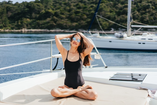 Free photo young healthy and calm woman doing yoga on sailing yacht boat in sea