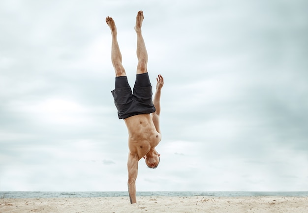 Free Photo young healthy man athlete doing squats at the beach