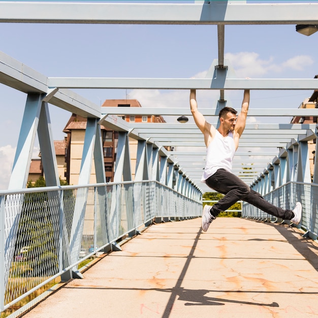 Free photo young healthy man hanging on bridge