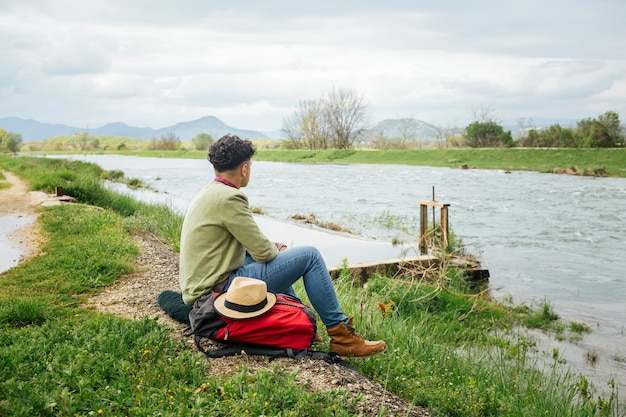 Free photo young hiker siting near beautiful river