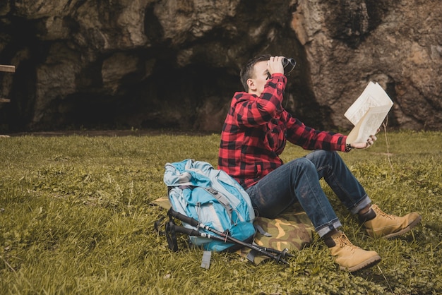 Free Photo young hiker using binoculars and holding a map