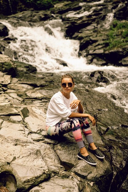 young hippie woman in bright leggings and round glasses in nature