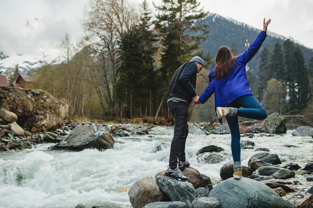 Free Photo young hipster beautiful couple in love walking on a rocks at river in winter forest