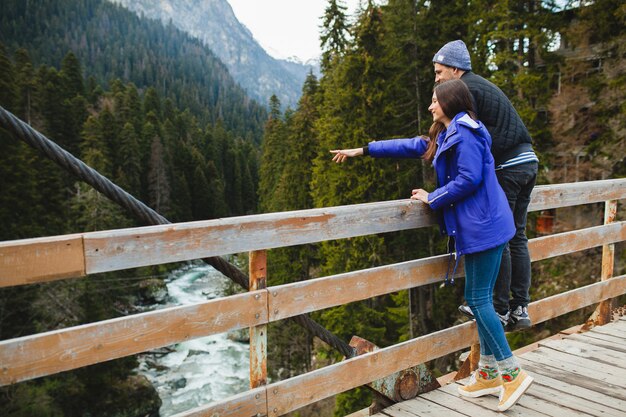 Young hipster beautiful couple in love, in winter forest, winter vacation in mountains