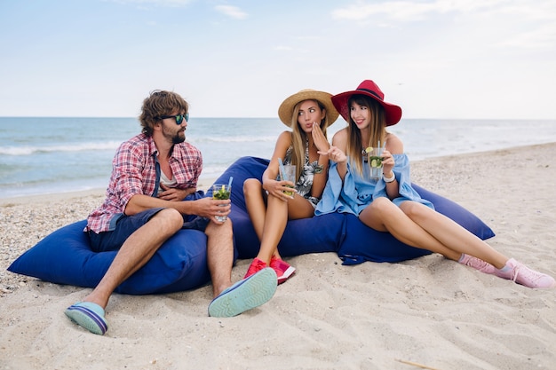 Young hipster company of friends on vacation at beach cafe, drinking mojito cocktail