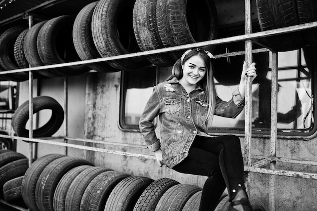 Young hipster girl in jeans jacket and head scarf at tire fitting zone