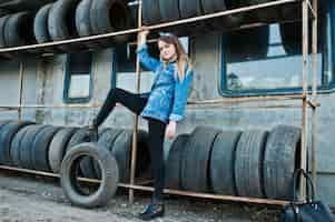 Free photo young hipster girl in jeans jacket and head scarf at tire fitting zone