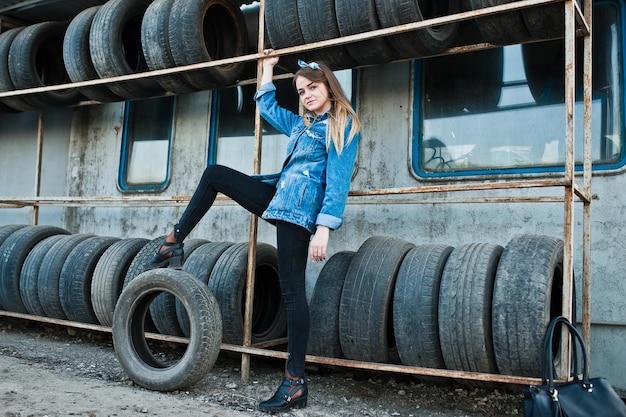 Free Photo young hipster girl in jeans jacket and head scarf at tire fitting zone