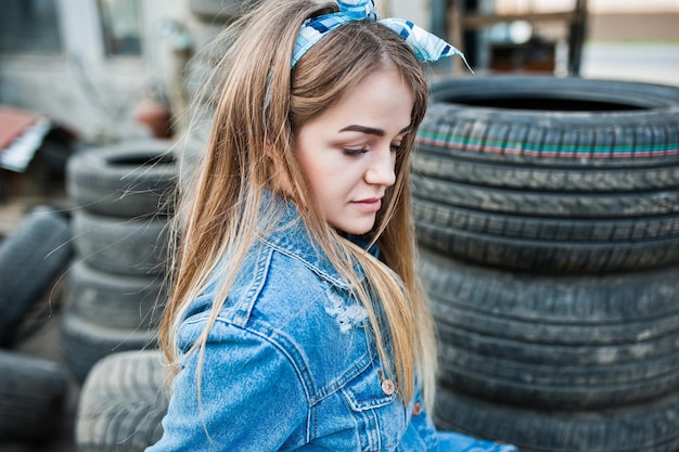 Free photo young hipster girl in jeans jacket and head scarf at tire fitting zone