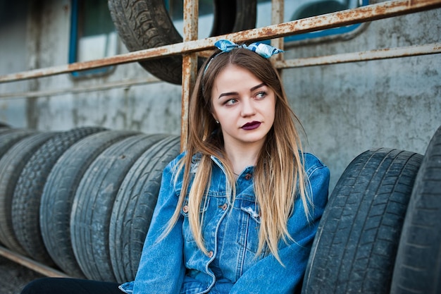 Young hipster girl in jeans jacket and head scarf at tire fitting zone