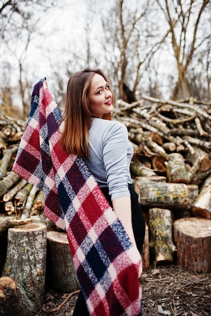 Free photo young hipster girl wear on blanket against wooden stumps on wood