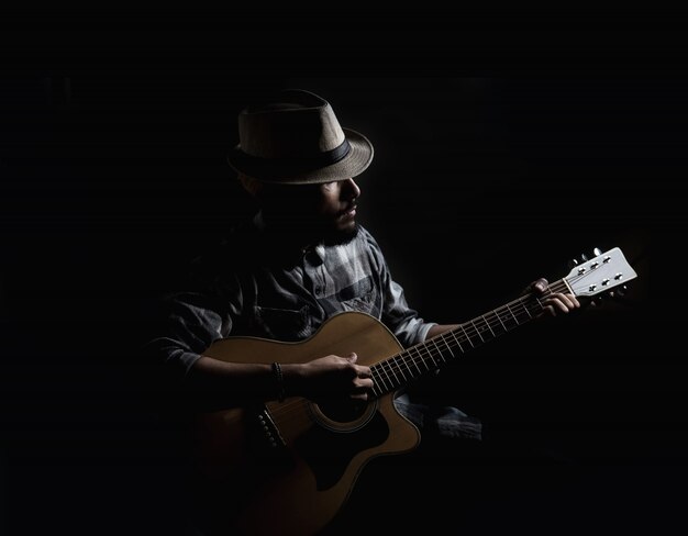 Young hipster guitarist play on the acoustic guitar .