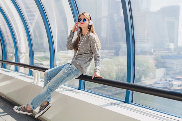 Free photo young hipster woman in casual outfit having fun listening to music in headphones