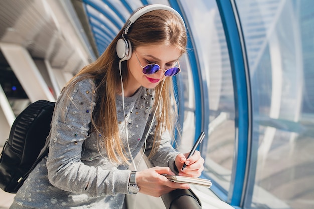 Free photo young hipster woman in casual outfit having fun listening to music in headphones