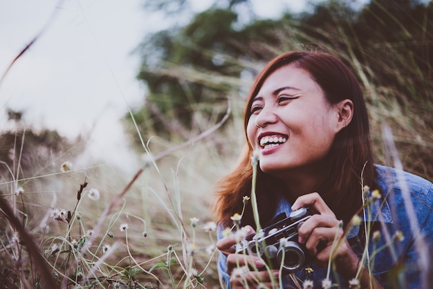 Free photo young hipster woman making photos with vintage film camera at summer field. women lifestyle concept.