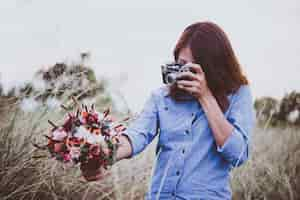 Free photo young hipster woman making photos with vintage film camera at summer field. women lifestyle concept.