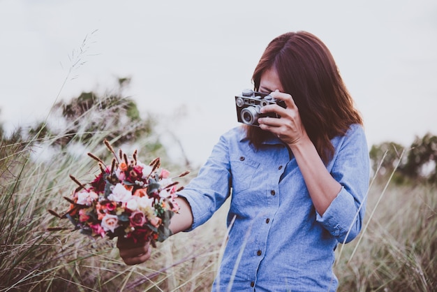 Free Photo young hipster woman making photos with vintage film camera at summer field. women lifestyle concept.