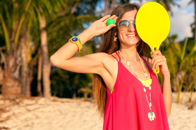 Young hipster woman playing ping-pong on tropical beach, summer vacation.