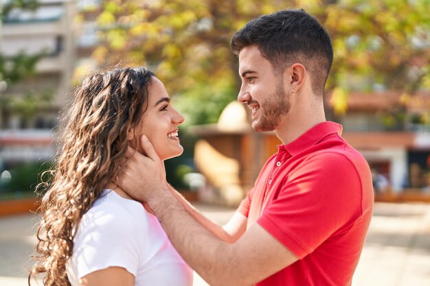 Young hispanic couple smiling confident hugging each other at park