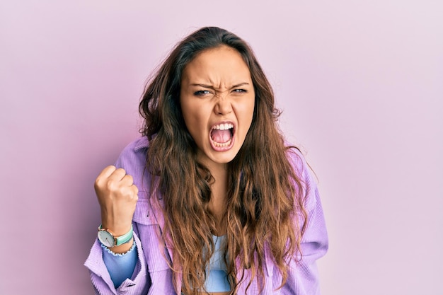 Free photo young hispanic girl wearing casual clothes angry and mad raising fist frustrated and furious while shouting with anger rage and aggressive concept