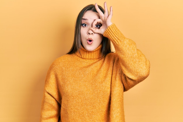 Free photo young hispanic girl wearing casual clothes doing ok gesture shocked with surprised face, eye looking through fingers. unbelieving expression.