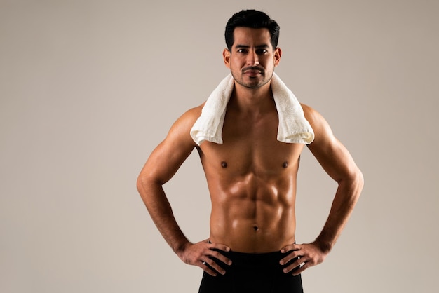 Young Hispanic male athlete with towel on neck and hands on hips