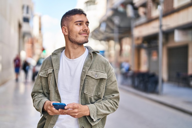 Free photo young hispanic man smiling confident using smartphone at street