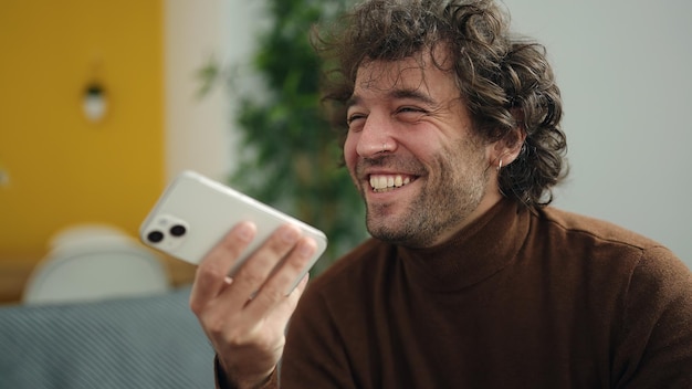 Free Photo young hispanic man talking on the smartphone sitting on sofa at home