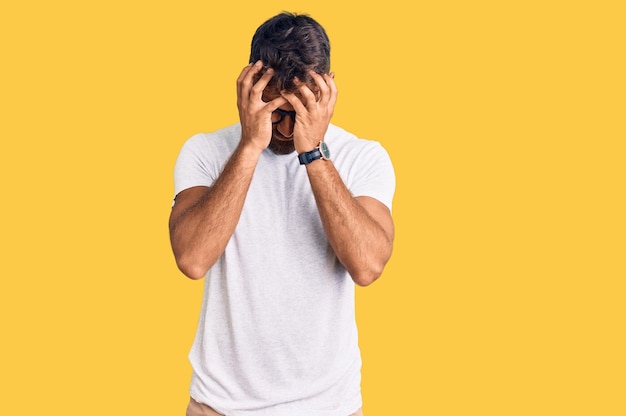 Young hispanic man wearing casual clothes and glasses suffering from headache desperate and stressed because pain and migraine. hands on head.