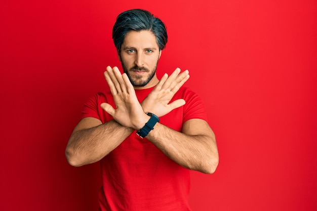 Free photo young hispanic man wearing casual red t shirt rejection expression crossing arms doing negative sign angry face