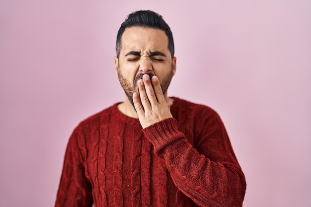 Free Photo young hispanic man with beard wearing casual sweater over pink background bored yawning tired covering mouth with hand restless and sleepiness