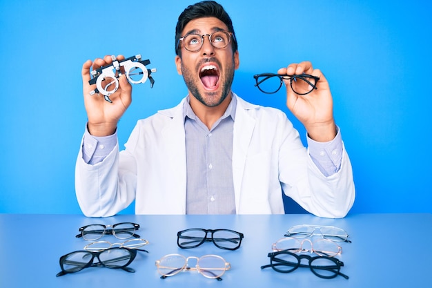 Free Photo young hispanic man with optometry glasses angry and mad screaming frustrated and furious, shouting with anger looking up.