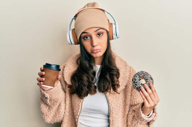 Free photo young hispanic woman using headphones having breakfast depressed and worry for distress crying angry and afraid sad expression