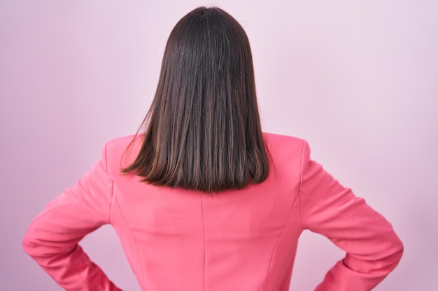 Free photo young hispanic woman wearing business clothes and glasses standing backwards looking away with arms on body