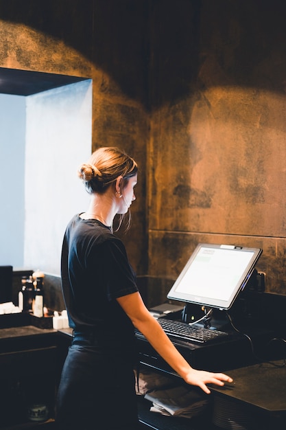 Free photo young hostess standing near cash register