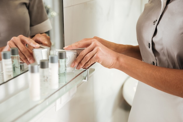 Young hotel maid putting bath accessories in a bathroom