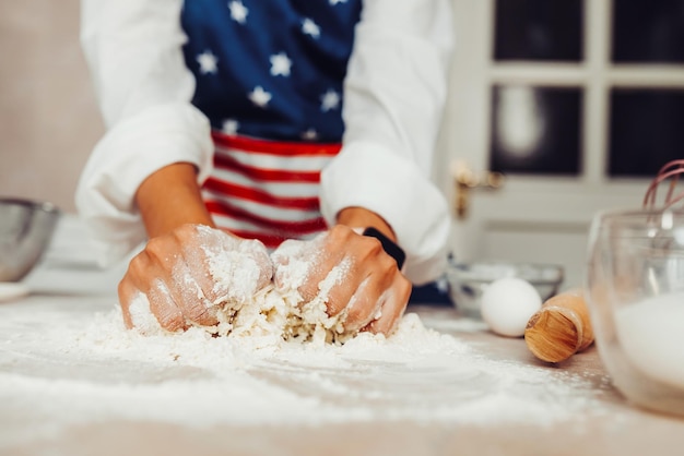 Young housewife in an apron kneads dough with her hands