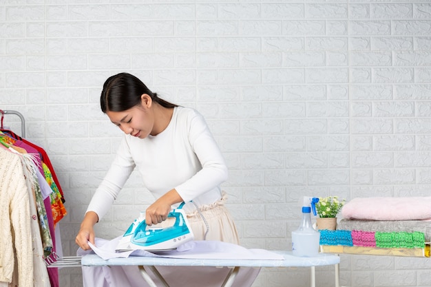 Young housewives who are using irons Ironing his clothes on a white brick .