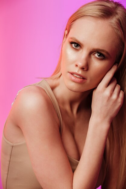 Young incredible woman standing and posing over pink wall