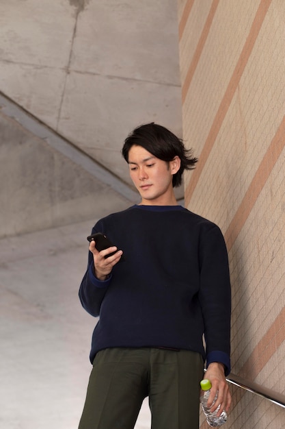 Free photo young japanese man in a blue sweater outdoors