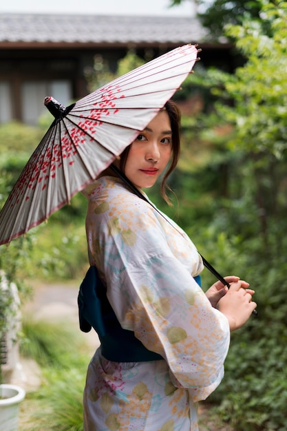 Free photo young japanese woman wearing a kimono and holding an umbrella