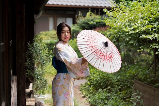 Free Photo young japanese woman wearing a kimono and holding an umbrella