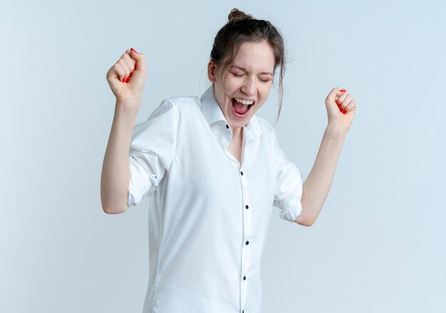 Young joyful blonde russian girl stands with raised fists isolated on white space with copy space