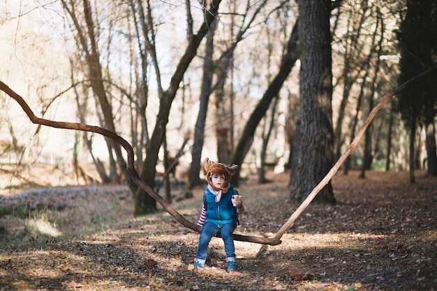 Free Photo young kid sitting on branch