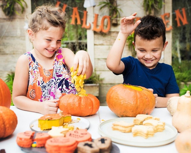 Free photo young kids carving halloween jack-o'-lanterns